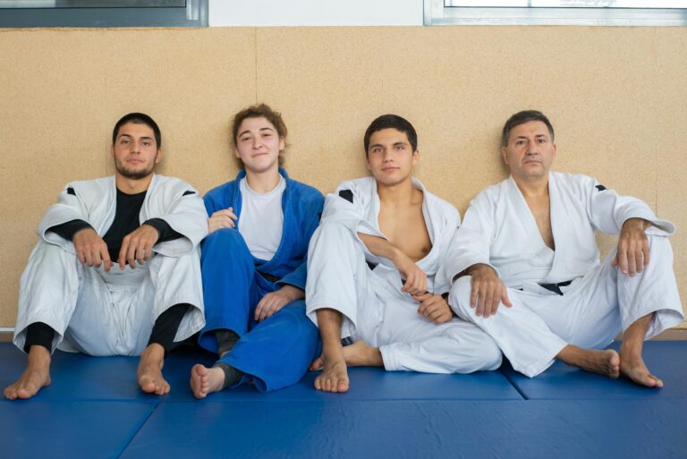 Four judo practitioners in gis sit together, showcasing teamwork and martial arts discipline.