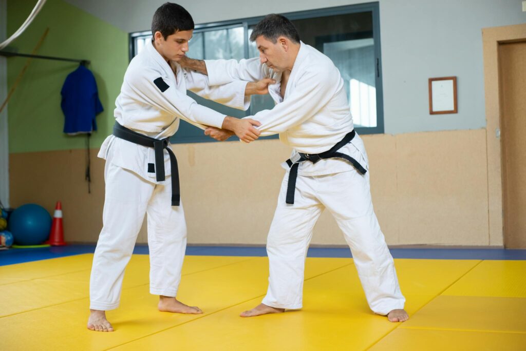 Two men engaged in a judo training session on a mat indoors. Strength and technique in action.