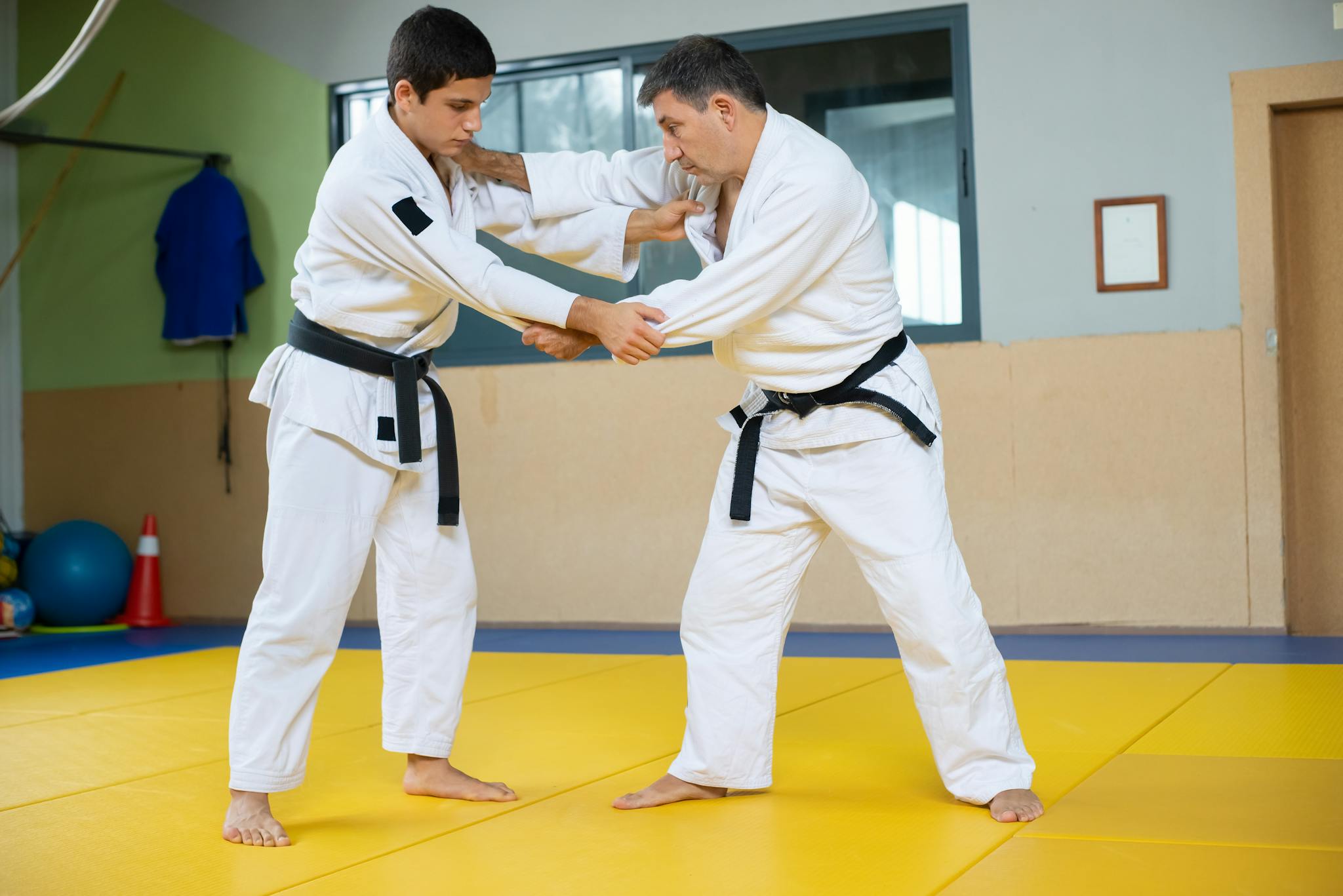 Two men engaged in a judo training session on a mat indoors. Strength and technique in action.